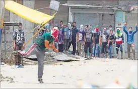  ?? WASEEM ANDRABI / HT PHOTO ?? A protester throws stones at policemen in Srinagar on Sunday.