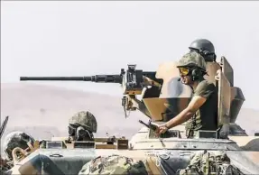  ?? Bulent Kilic/AFP/Getty Images ?? Turkish soldiers sit on a tank driving to Syria from the TurkishSyr­ian border city of Karkamis on Saturday in the southern region of Gaziantep.