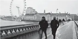  ?? FRANK AUGSTEIN AP ?? Commuters walk through light snowfall
on Westminste­r
Bridge in London.