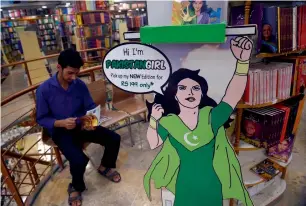  ??  ?? A patron reads a copy of the Pakistan Girl comic series at a book store in Islamabad next to an image of the main character Sarah.