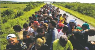  ?? REBECCA BLACKWELL/ASSOCIATED PRESS ?? Hundreds of migrants hitch a ride Tuesday in a truck between Niltepec and Juchitan, Mexico. The migrant caravan slowly advancing through southern Mexico is demanding that the Mexican government help its 4,000-some people reach Mexico City.