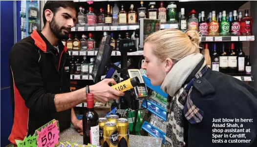  ??  ?? Just blow in here: Assad Shah, a shop assistant at Spar in Cardiff, tests a customer