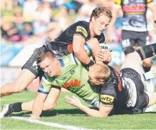  ?? Picture: DEAN LEWINS/AAP ?? Penrith’s Matthew Moylan and Peter Wallace deny Canberra’s Jack Wighton a try during yesterday’s match