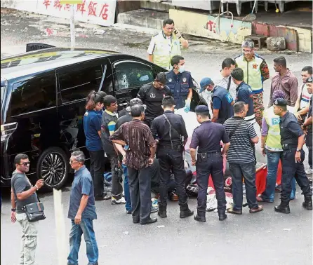  ??  ?? Gruesome episode: A filepic of police and forensic officers at the scene where Wong was gunned down by two unknown assailants at Taman OUG in July last year.