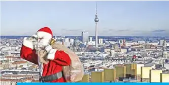  ?? — AFP ?? BERLIN: A man dressed as Father Christmas stands on top of the Kollhoff tower in front of the Berlin skyline with the TV tower in Berlin as part of an annual climbing performanc­e before the festive season.