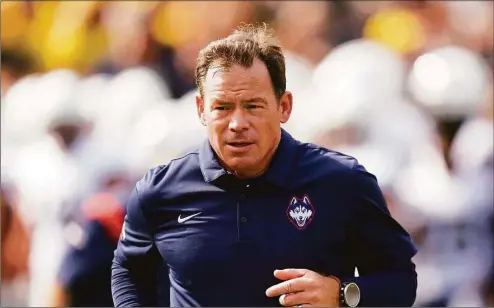  ?? Paul Sancya / Associated Press ?? UConn coach Jim Mora runs before an NCAA college football game against Michigan Sept. 17 in Ann Arbor, Mich.