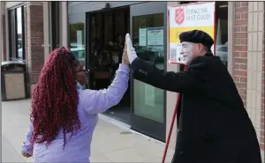  ?? (Arkansas Democrat-Gazette/Dale Ellis) ?? Marvin Fisher of Sherwood, a Salvation Army volunteer bell ringer, gets a high-five from Kristina Scott of Little Rock as she passes by the entrance of Hobby Lobby in North Little Rock. Maj. Bill Mockabee, the head of the Central Arkansas Salvation Army, said Fisher is a longtime volunteer. “He always has costumes of some sort on,” Mockabee said. “He makes it fun.”