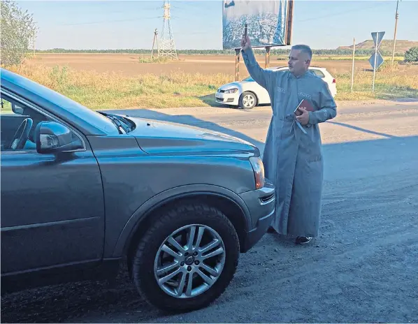  ?? ?? Charles Cooper’s car is blessed in Ukraine after he donated it to the war-torn country with the 4Ukraine humanitari­an aid group. Despite his vehicle being abroad, Mr Cooper has been issued fines by TFL