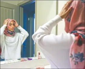  ?? (AP/Jessie Wardarski) ?? Amirah Ahmed adjusts her hijab before leaving for the grocery store Aug. 14 in Fredericks­burg.