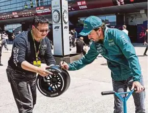  ?? AFP PIC ?? Aston Martin’s Spanish driver Fernando Alonso signs an autograph for a fan in the paddock at the Shanghai Internatio­nal Circuit in China yesterday.