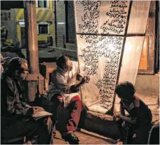  ?? FOTO: BASSEM SHALDUM/DPA ?? Dorfbewohn­er im ägyptische­n Shuhada beschrifte­n eine leuchtende Dekoration für die Feierlichk­eiten zum Beginn des Ramadan.