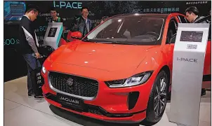  ?? AP ?? People look at a Jaguar electric-powered I-Pace SUV earlier this year at an auto show in Beijing. Jaguar Land Rover and other rivals of Tesla Inc. are moving aggressive­ly into the luxury electric vehicle field.