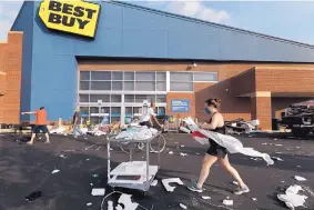  ?? CHARLES REX ARBOGAST/ASSOCIATED PRESS ?? Volunteers help clean up the parking lot outside a Best Buy store Monday after vandals struck overnight in the Lincoln Park neighborho­od in Chicago. Chicago’s police commission­er says more than 100 people were arrested following a night of looting.