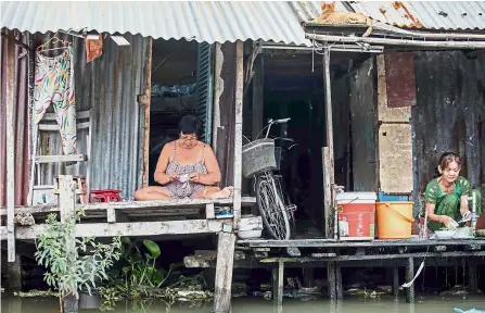  ?? — AFP ?? Waiting to leave: Thanh (left) on her porch on the Xuyen Tam canal in Ho Chi Minh City, Vietnam.