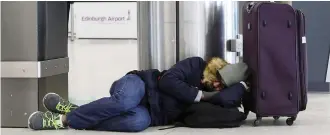  ??  ?? Stuck: A passenger sleeps at Edinburgh Airport yesterday after cancellati­ons