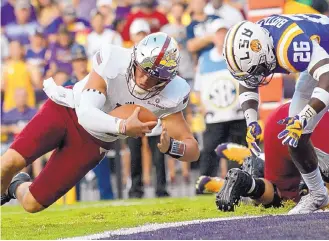  ?? MATTHEW HINTON/ASSOCIATED PRESS ?? Troy quarterbac­k Brandon Silvers (12) beats LSU safety John Battle to the point of contact and scores a touchdown in the Trojans’ stunning 24-21 win on Saturday night in Baton Rouge, La.