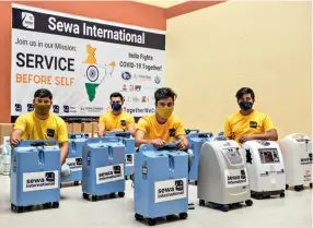  ??  ?? BREATHING EASY Sewa Internatio­nal members distribute oxygen concentrat­ors at a Delhi Covid care centre