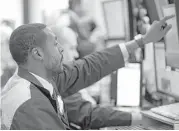  ?? Mark Lennihan / Associated Press ?? Trader Aaron Ford works Wednesday at the New York Stock Exchange. The markets had little reaction to the Federal Reserve raising a key interest rate.