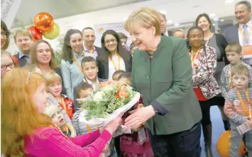 ?? — Reuters ?? German Chancellor and leader of the Christian Democratic Union party CDU Angela Merkel receives flowers from an associatio­n of multiple child families before the start of the final day of the CDU party convention in Essen, Germany, on Wednesday.