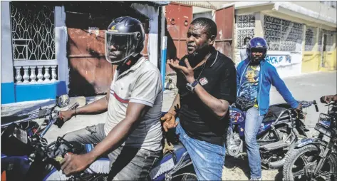  ?? AP PHOTO/ODELYN JOSEPH ?? Jimmy Cherizier, the leader of the “G9 et Famille” gang, talks with members of his gang while taking a ride on the back of a motorcycle in his district of Delmas 6 in Port-au-Prince, Haiti, on Jan. 24.
