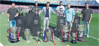  ??  ?? Con los trofeos obtenidos con el Barça y los capitanes del equipo, en los que resalta Messi.