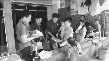  ??  ?? Dennis (third left) and the JPN team help a Penan family with their applicatio­n.