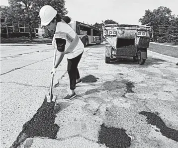  ?? PAUL SANCYA/AP 2018 ?? Michigan’s Democratic Gov. Gretchen Whitmer, who won election after running on the slogan “Fix the Damn Roads,” fills a pothole during a campaign event in Southfield, Mich. Her plan would add 45 cents to the cost of a gallon of gas by 2020.