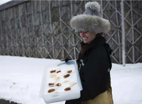  ?? MELISSA RENWICK PHOTOS/TORONTO STAR ?? Ellen Wilkes Irmisch, resource interprete­r with Conservati­on Halton, carries fresh maple taffy rolled around Popsicle sticks near Campbellvi­lle. Ont.