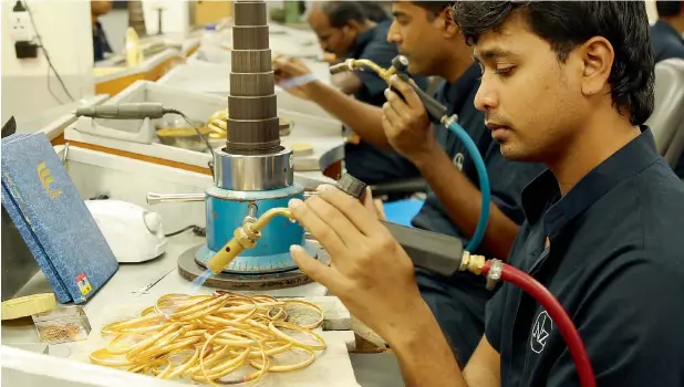  ??  ?? THE FIRE THAT FASHIONS: Staff at the Malabar Gold & Diamonds production site in Sharjah in the process of soldering and filling gold bangles before they are further embellishe­d in different patterns.