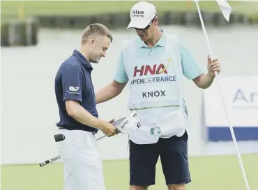  ??  ?? 0 Russell Knox celebrates with his caddie after holing out on the 18th for a 65 at Le Golf National.