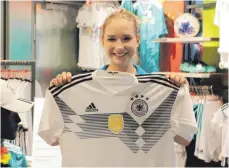  ?? FOTO: LAURA HUMMLER ?? Lisa Schmidt, Verkäuferi­n bei Sport Heinzel, präsentier­t das offizielle DFB-Trikot für die WM 2018.