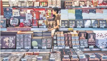  ??  ?? A woman walks past mooncakes (front) for sale at a bakery inside a train station in Hong Kong. — AFP photo