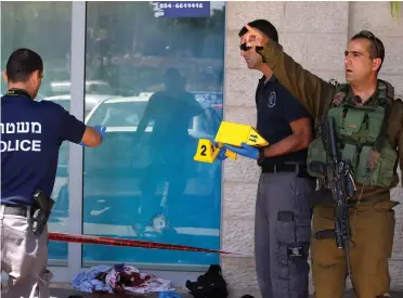  ?? (Ronen Zvulun/Reuters) ?? SECURITY PERSONNEL at the Gush Etzion Junction near the scene of the stabbing attack.