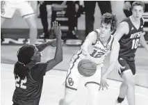  ??  ?? Oklahoma's Austin Reaves (12) passes the ball around UTSA's Keaton Wallace (22) during a Dec. 3 game against the Roadrunner­s at Lloyd Noble Center in Norman. [BRYAN TERRY/ THE OKLAHOMAN]