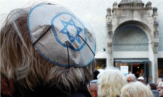  ?? (Fabrizio Bensch/Reuters) ?? PEOPLE WEAR kippot as they attend a demonstrat­ion in front of a Jewish synagogue in Berlin on Wednesday to denounce an antisemiti­c attack on a young man wearing a kippa in the capital earlier this month.