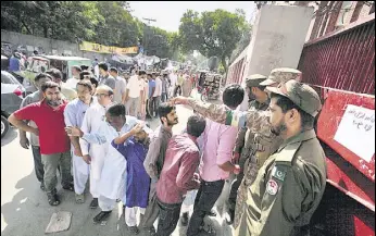  ?? REUTERS ?? Soldiers stand guard as voters queue up to vote outside a polling station in Lahore.