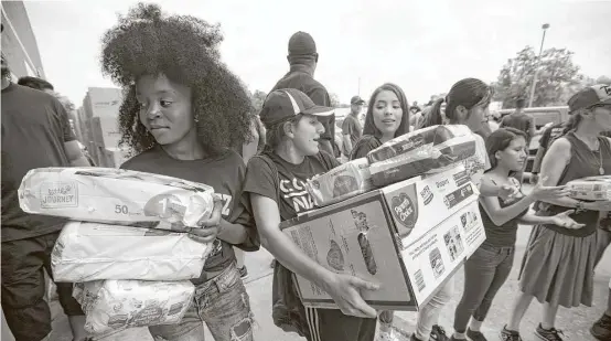  ?? Brett Coomer / Houston Chronicle ?? Student volunteer Nahimana Pascaziya, left, passes along diapers while helping to distribute relief supplies to people impacted by Hurricane Harvey.