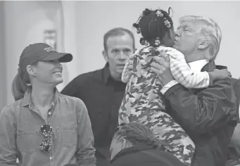  ?? SUSAN WALSH/AP ?? President Donald Trump kisses a child as his wife, Melania, looks on Saturday during a visit to the NRG Center in Houston to meet some of the victims of Hurricane Harvey. It was his second trip to Texas in a week.