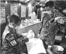  ??  ?? A military dentist and his assistant providing free dental checks to one of their patients yesterday.