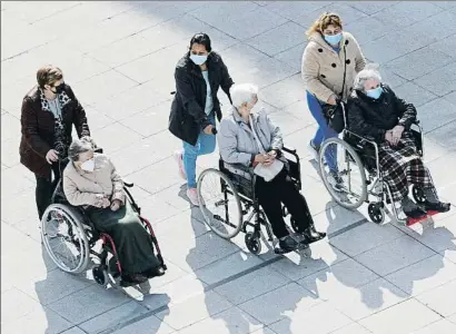  ?? LUIS TEJIDO / EFE ?? Familiars i cuidadores passegen tres dones grans que resideixen en un asil del País Basc