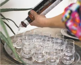  ??  ?? Above: Vodka is poured for a tasting during a distillery tour. Below: Tasting room associate Julia Hadas, left, takes a photo of a group at Hangar 1 Vodka.