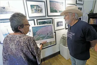  ?? LUIS SÁNCHEZ SATURNO/THE NEW MEXICAN ?? Photograph­er Lisa Law shows Gary Nicholson, a musician from Nashville, Tenn., one of her prints from Woodstock at the Museum of the Sixties on Monday in Santa Fe. The temporary exhibit is open through the end of the month.