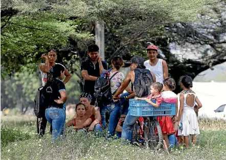  ??  ?? Venezuelan migrants rest under a tree near the Internatio­nal bridge Tienditas, on the outskirts of Cucuta, Colombia, on the border with Venezuela. Venezuelan opposition leader Juan Guaido is moving ahead with plans to try to bring in humanitari­an aid through the city, where the US government will transport and store food and medical supplies destined for Venezuela.