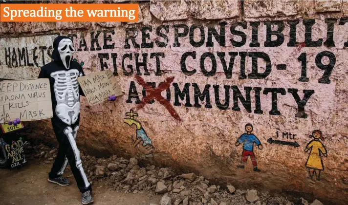  ??  ?? James Kiriva, 35, who took the initiative to educate his community about the importance of taking precaution­s to curb the spread of the coronaviru­s, walks around dressed as a skeleton to spread his message in English and Swahili, past an informatio­nal mural, in the Kibera low-income neighborho­od of Nairobi, Kenya yesterday. Photo: AP