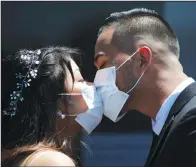  ?? (File Photo/AP/Jae C. Hong) ?? Roselle Querido (left) and Mo de las Alas kiss May 26, 2020, after their marriage service in the parking lot of Honda Center in Anaheim.