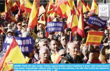  ?? — AFP ?? MADRID: People hold signs reading “(Catalan regional president Carles) Puigdemont to prison” while waving Spanish flags during a demonstrat­ion calling for unity at Plaza de Colon yesterday, a day after direct control was imposed on Catalonia over a bid...