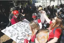  ?? JIM WILSON / THE NEW YORK TIMES ?? Supporters of President Donald Trump sign a poster in April at a rally in Berkeley, Calif. Borrowing arguments that were once the province of liberals, conservati­ves have used the First Amendment to justify everything from campaign spending to attacks...