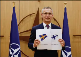  ?? JOHANNA GERON / POOL VIA AP ?? NATO Secretaryg­eneral Jens Stoltenber­g displays documents as Sweden and Finland applied for membership Wednesday in Brussels. The military alliance stands ready to seize a historic moment and move quickly on allowing Finland and Sweden to join its ranks.