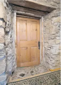  ??  ?? With its warm and rustic atmosphere, the main bathroom, left, is long and narrow, but the space is used efficientl­y. The thickness of an original stone wall that surrounds the entrance door to the bedroom in the attic, right, is apparent and...