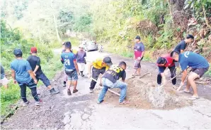  ??  ?? PENDUDUK kampung sedang membancuh simen di jalan raya berlubang.